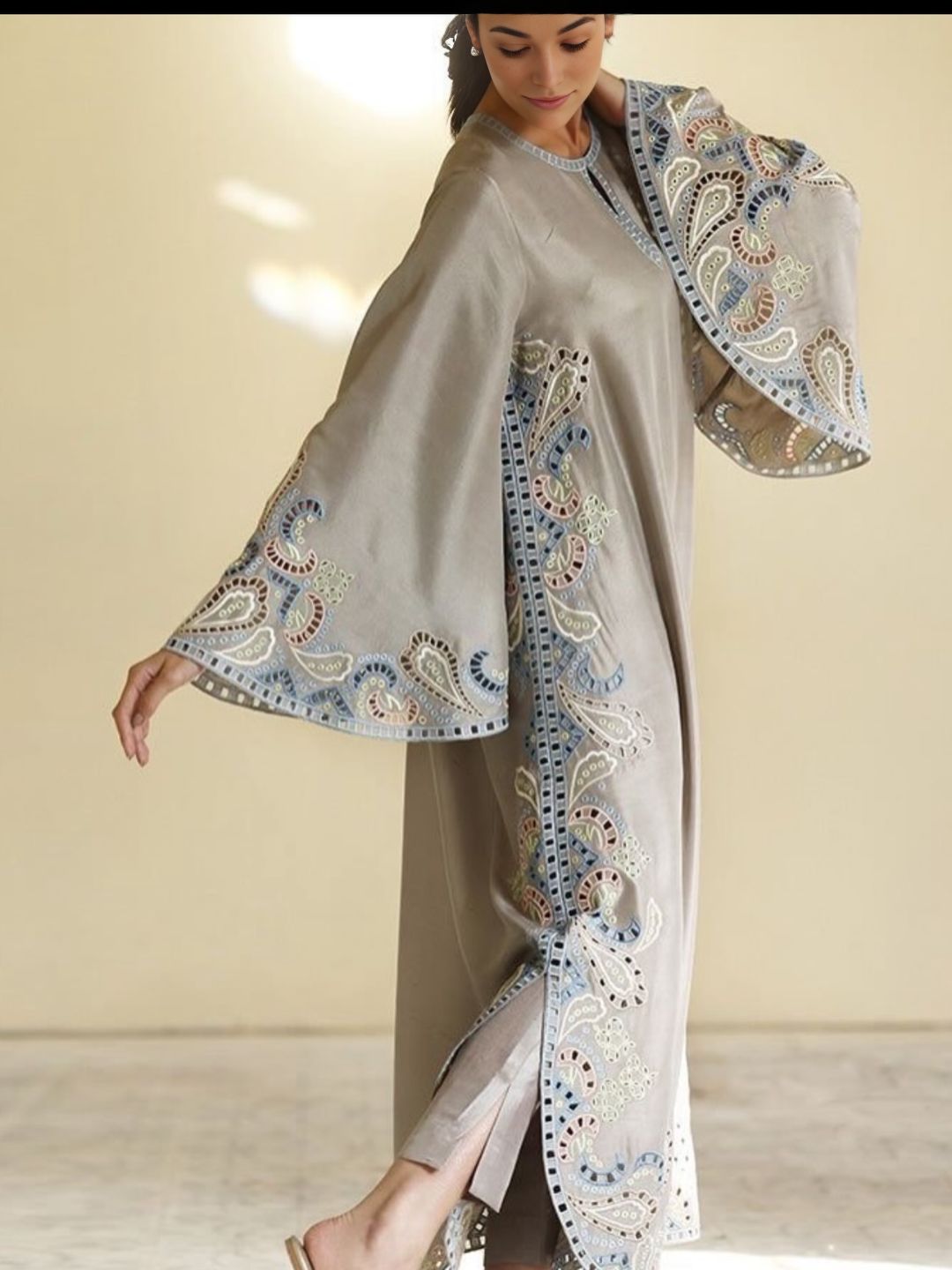 Woman wearing a gray dress with intricate paisley patterns on a plain background